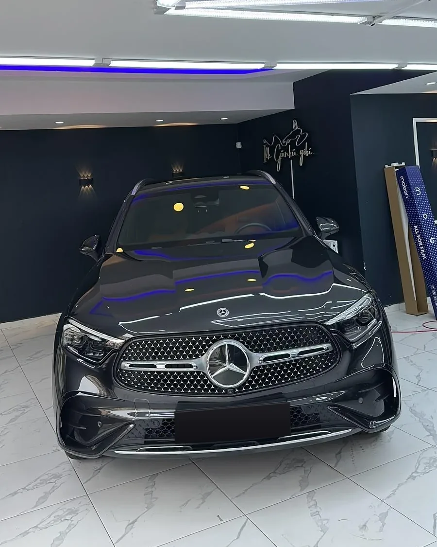 Stüdyoda parlatılmış siyah Mercedes GLC, arkada İlk Günkü gibi neon tabelası
