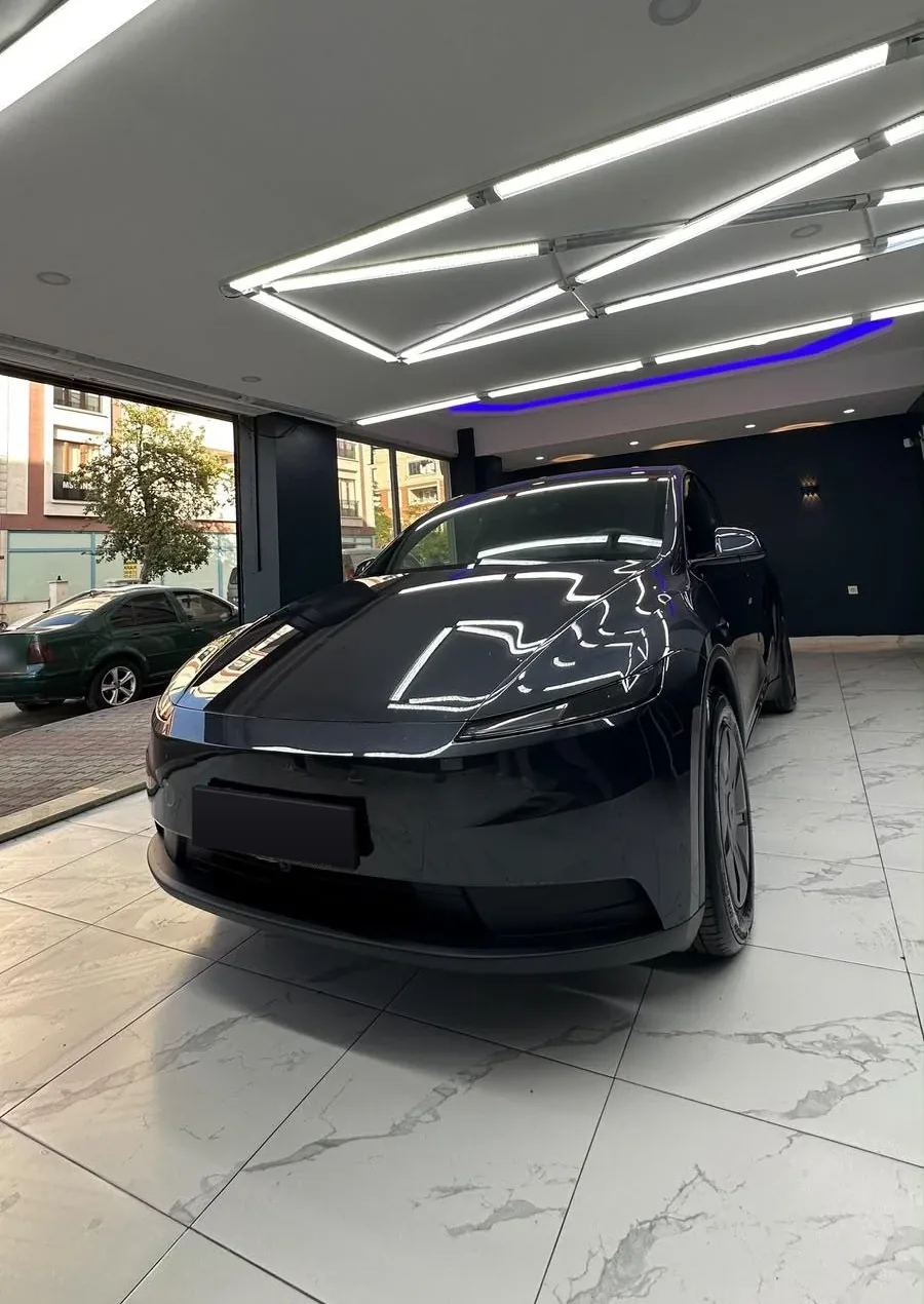 Stüdyoda şerit LED ışıklar altında parlayan koyu gri Tesla Model Y